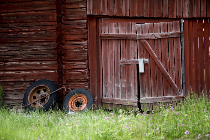 Bild på gammal rödmålad ladugård med lite sneda dörrar