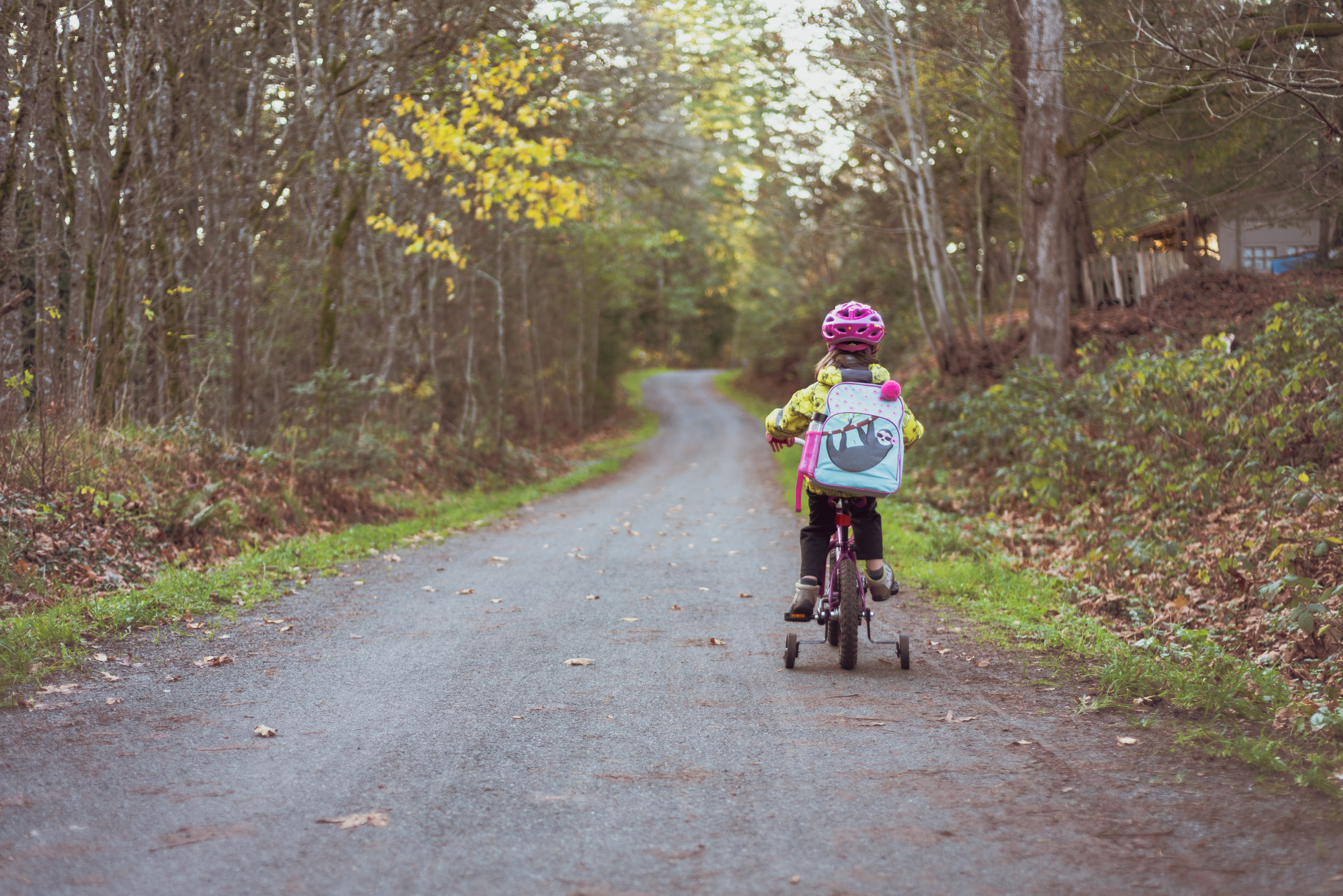 Barn på trehjulig cykel som färdas på en mindre villagata