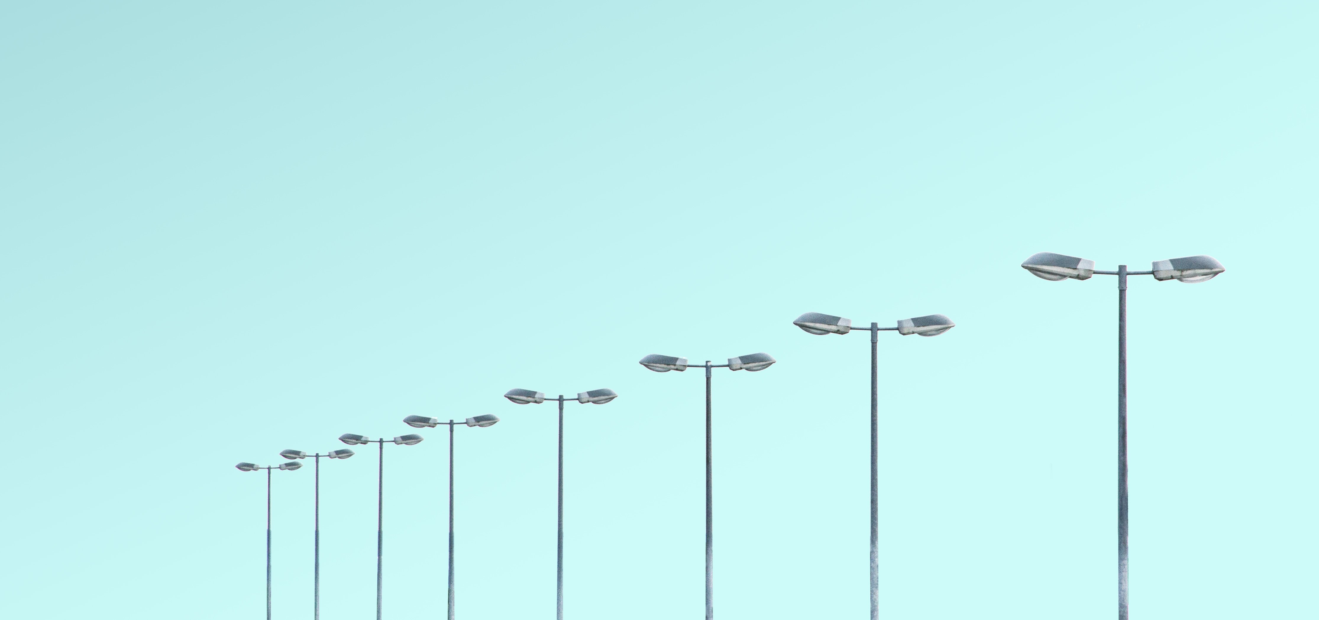 Bild som visar toppen av 8 lyktstolpar mot en blå himmel