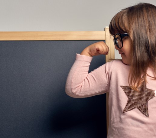 Flicka med brunt hår och glasögon spänner armen 